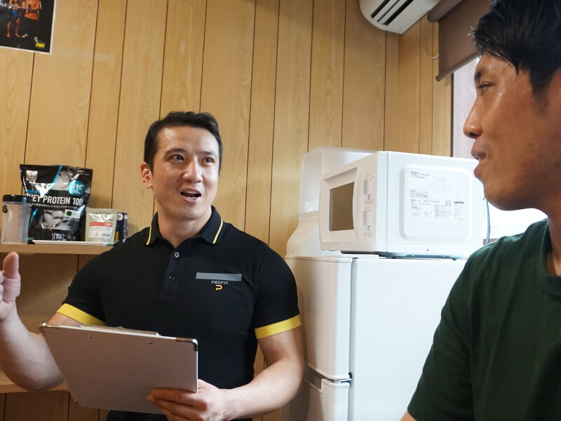 トレーナーが男性にフィットネスプランについて説明している。